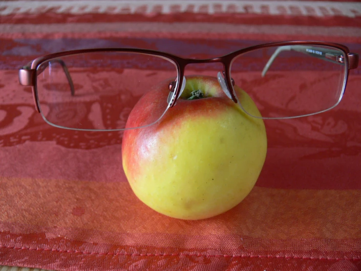 a red table with glasses and an apple on it