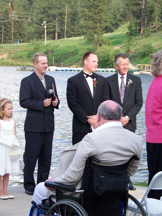 men and women standing around a man sitting in a wheel chair