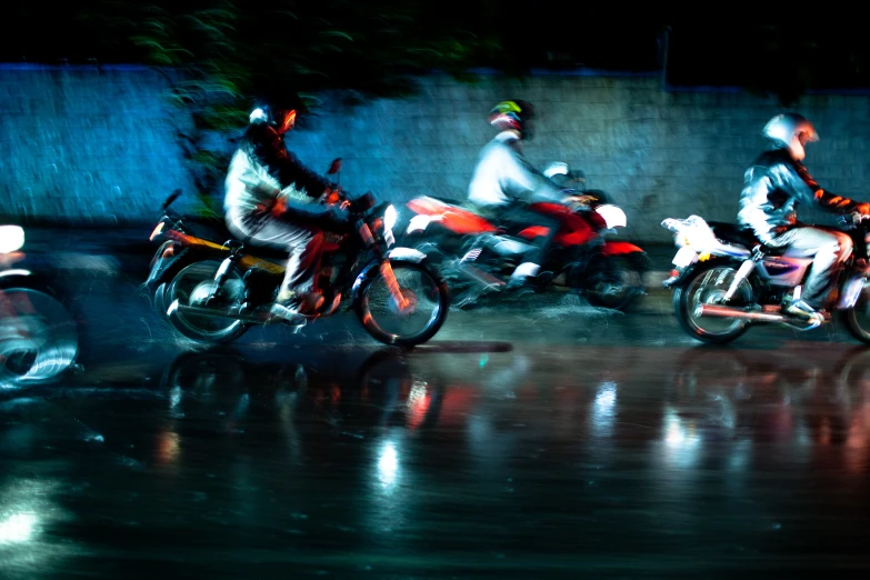 three motorcyclists on street in the rain