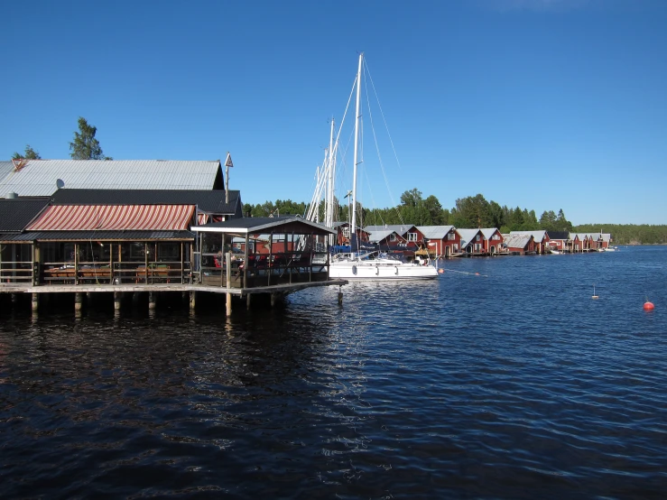 boats parked along a pier with other small buildings