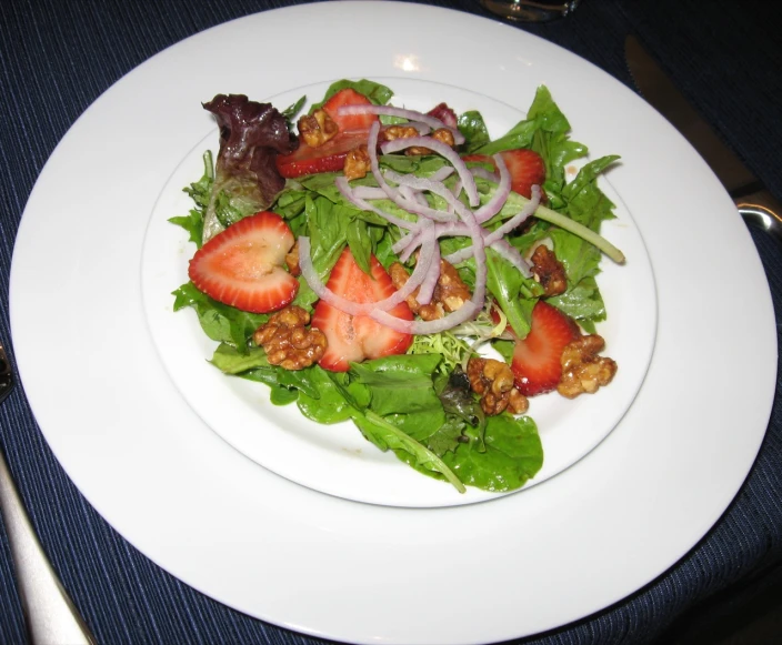 a white plate topped with salad and strawberries