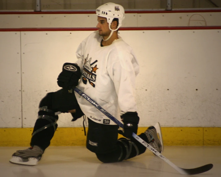 a goalie sitting on the ice holding a hockey puck