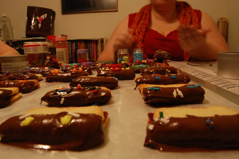 a woman is making decorated donuts on a sheet