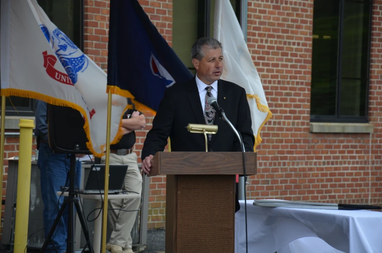 a man in suit and tie standing behind a podium speaking at an event