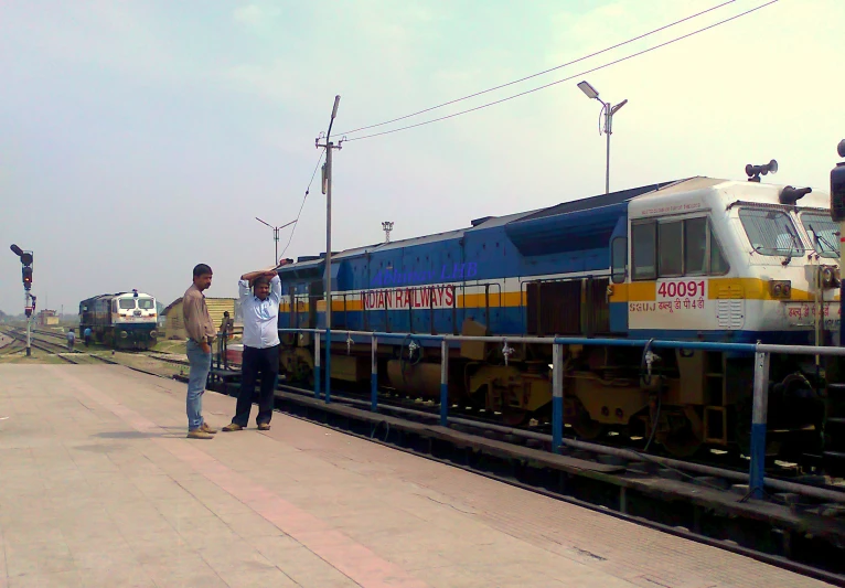 a man in a tan jacket is standing next to a train on the tracks