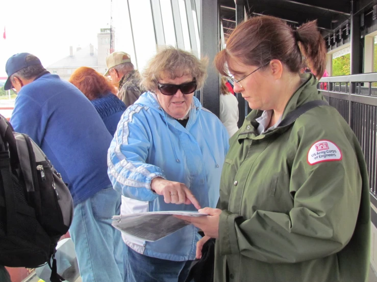 two women are standing together, and looking at a book