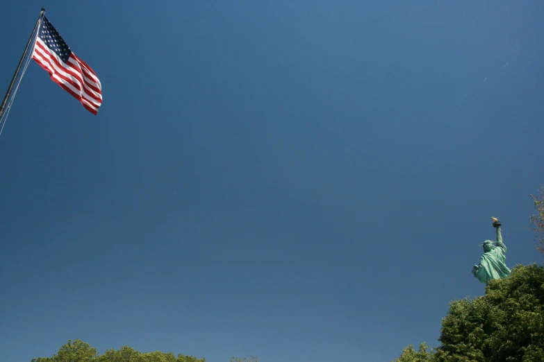 the statue of liberty, with an american flag, is in the air