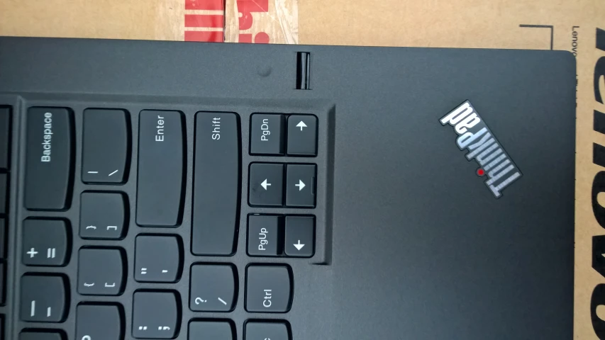 an opened laptop with stickers on it sits in a cardboard box