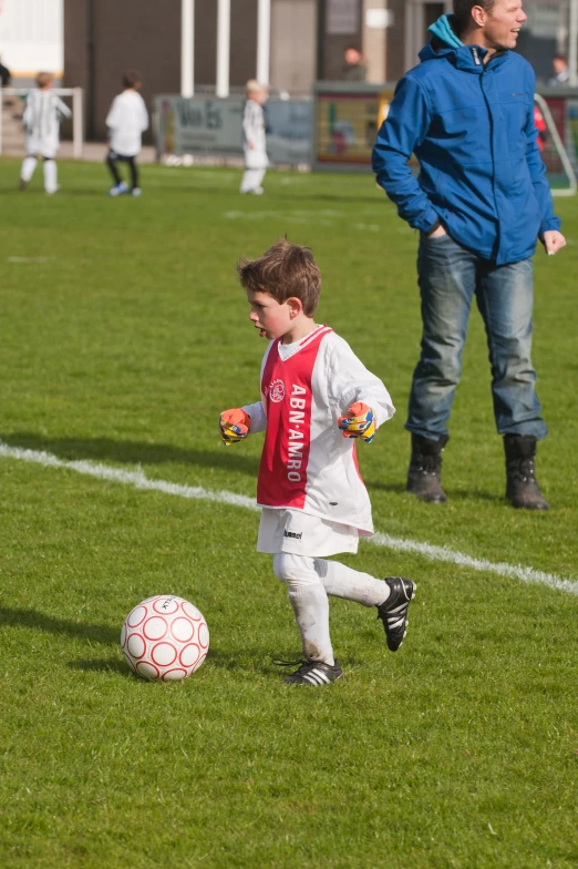 a young child on the field kicking a soccer ball