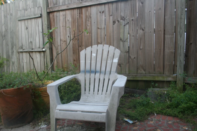 white chair next to a wooden fence, looking very old