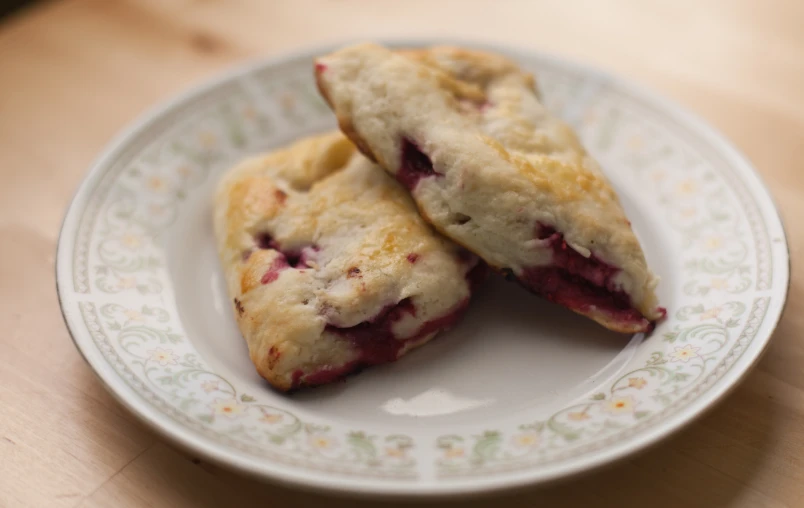 two strawberry filled pastries on a plate with some flowers