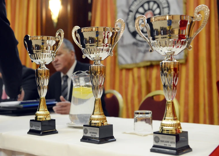 trophies sitting on a table with people sitting around them