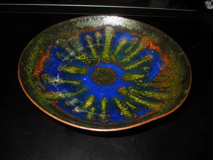 blue, yellow and green dish with white flowers in it