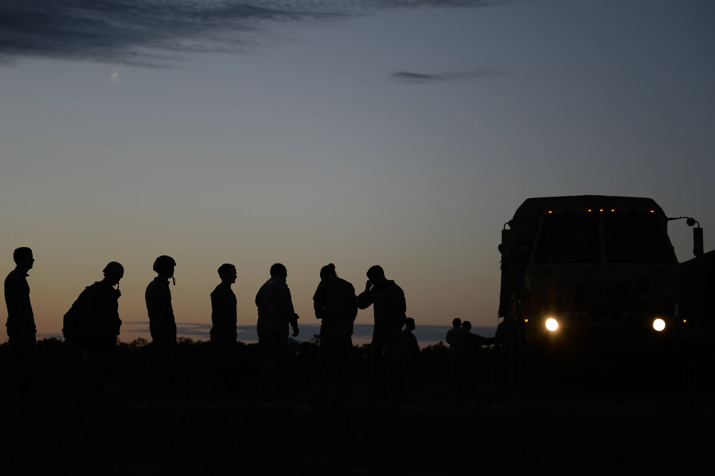 a silhouette of five people and a semi truck