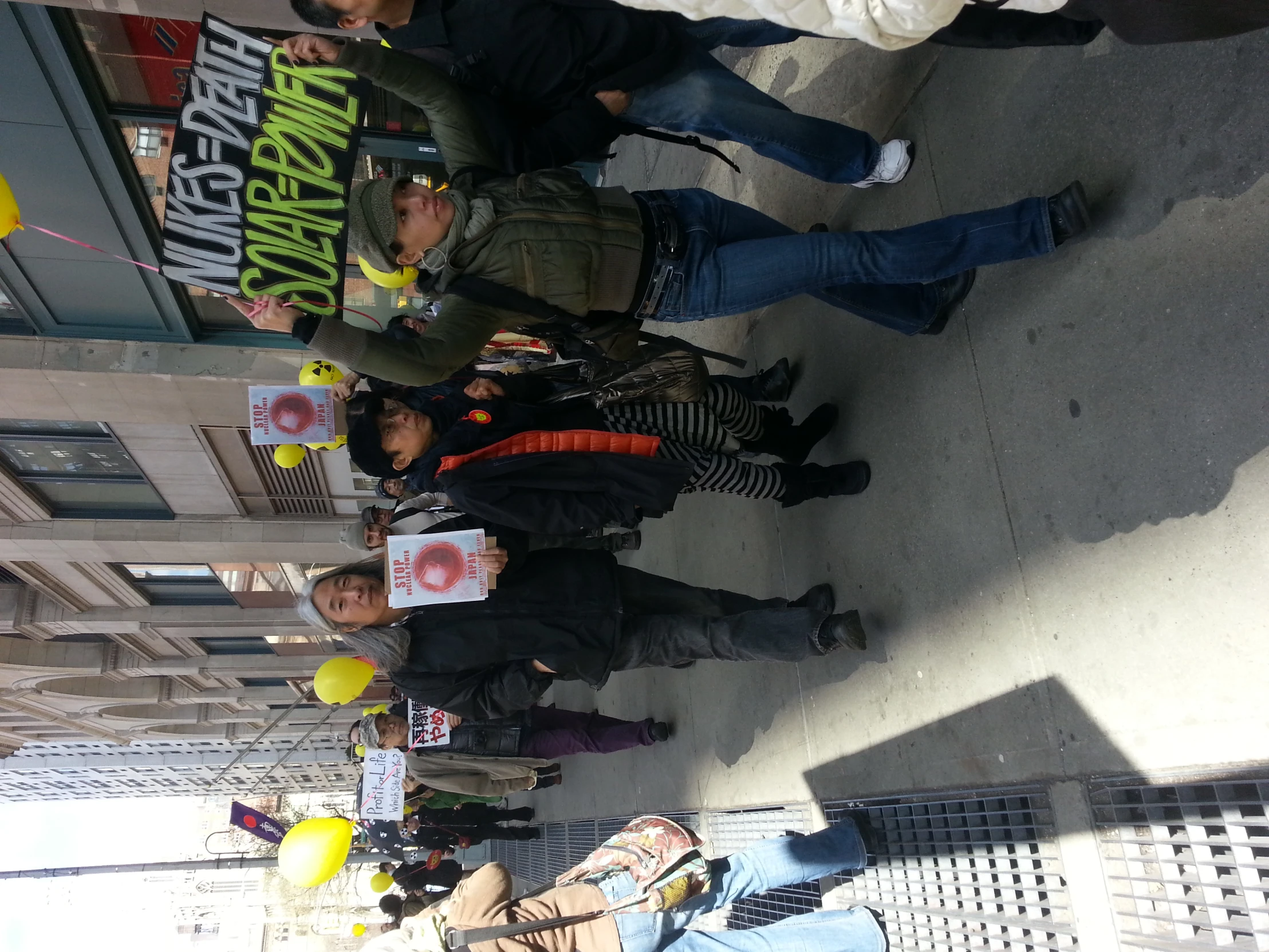 protesters with signs holding balloons march down a street