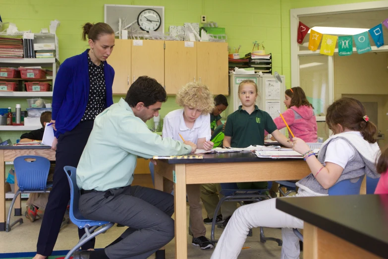 children are sitting around a teacher doing soing they wrote