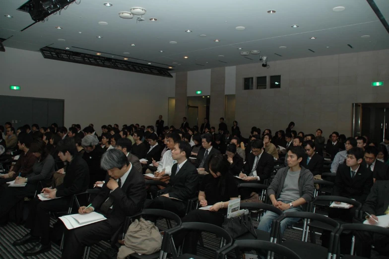 an office audience is watching an asian seminar