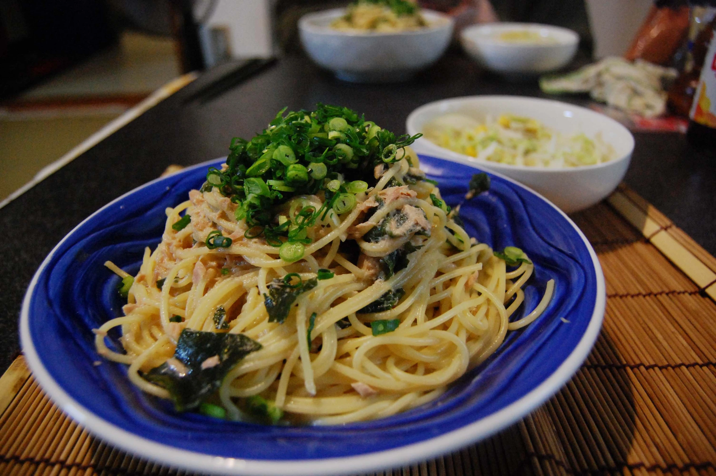 the plate contains noodles and vegetables, and the bowl is next to it