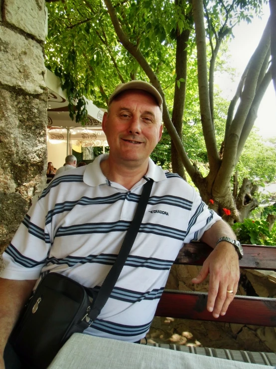 a man sits at an outdoor restaurant with an object in his hand