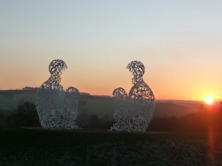 there are two sculptures of people and sun in the sky