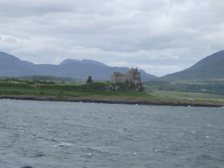 a small castle surrounded by water on a cloudy day