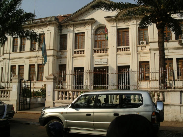 an older white building with a van driving by it