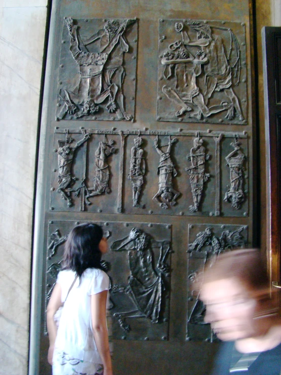 a woman walking past a decorative wall in a building