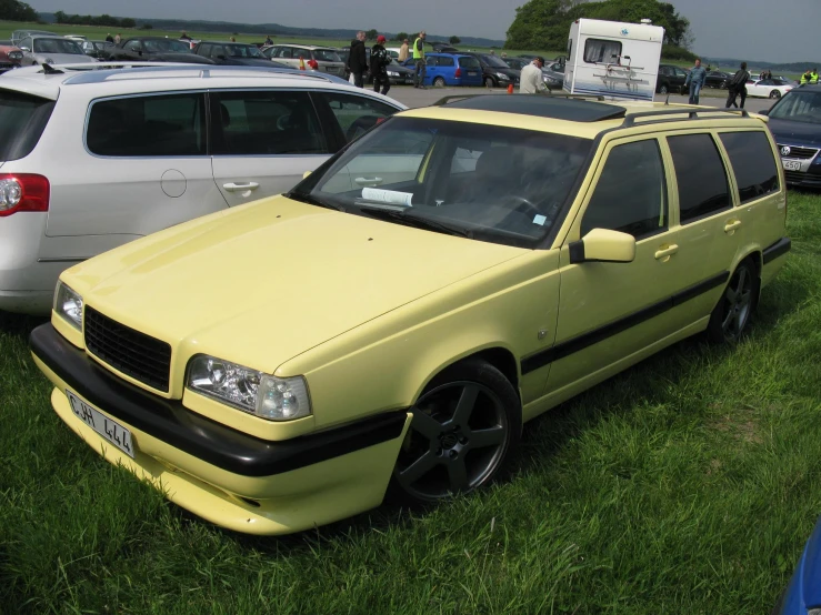 several cars parked on green grass with people in the background