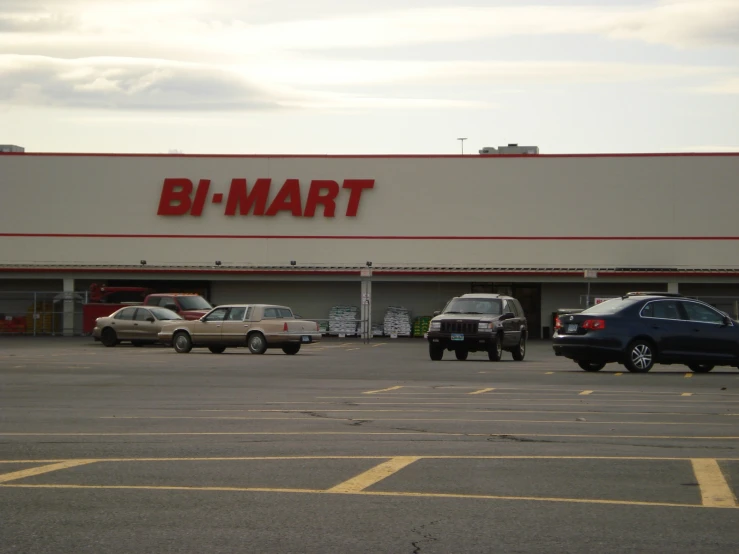 cars parked outside a bj mart store with vehicles parked on the lot