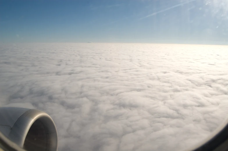 an airplane wing flying over clouds below it