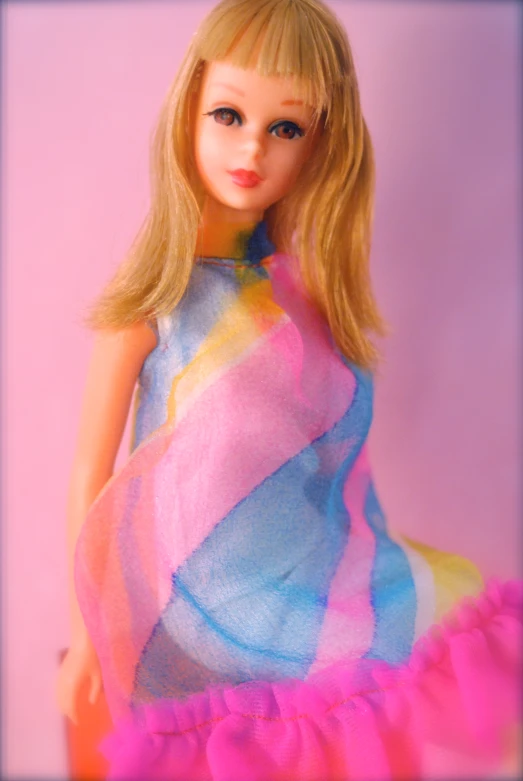 a barbie doll standing up in front of a pink wall