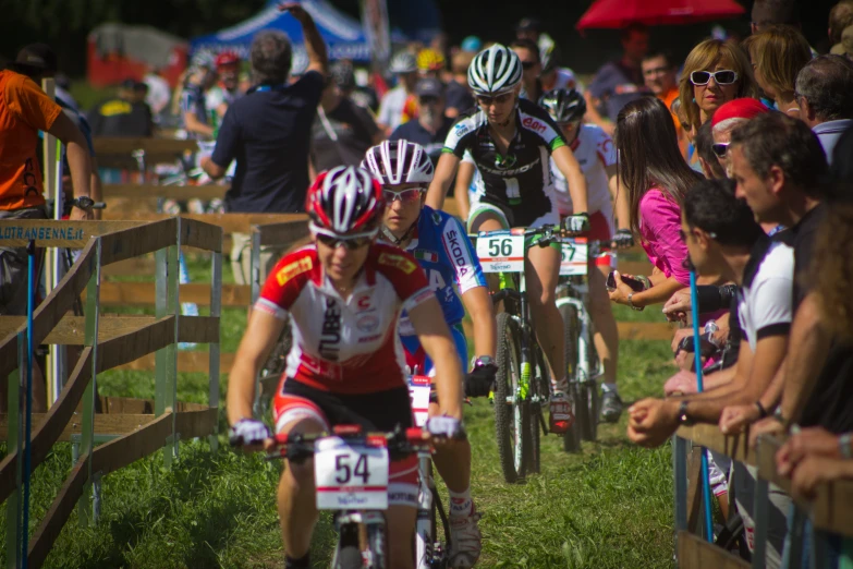 the group of bicyclists are riding past a crowd