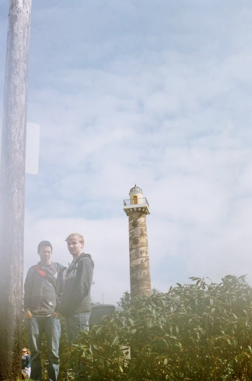 the two men stand next to a light house