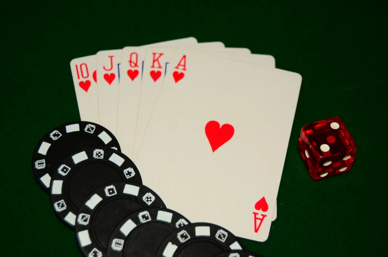 a pile of fours playing cards next to a red dice