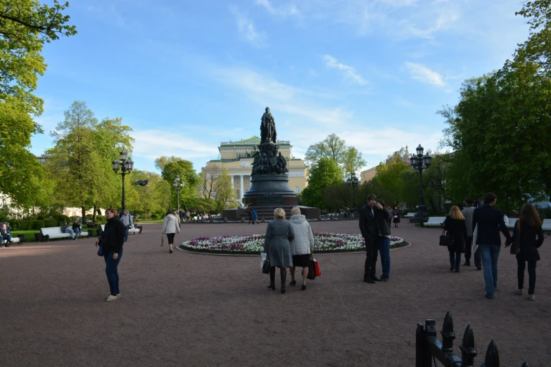 people walking around a park area with a fountain and gazebos