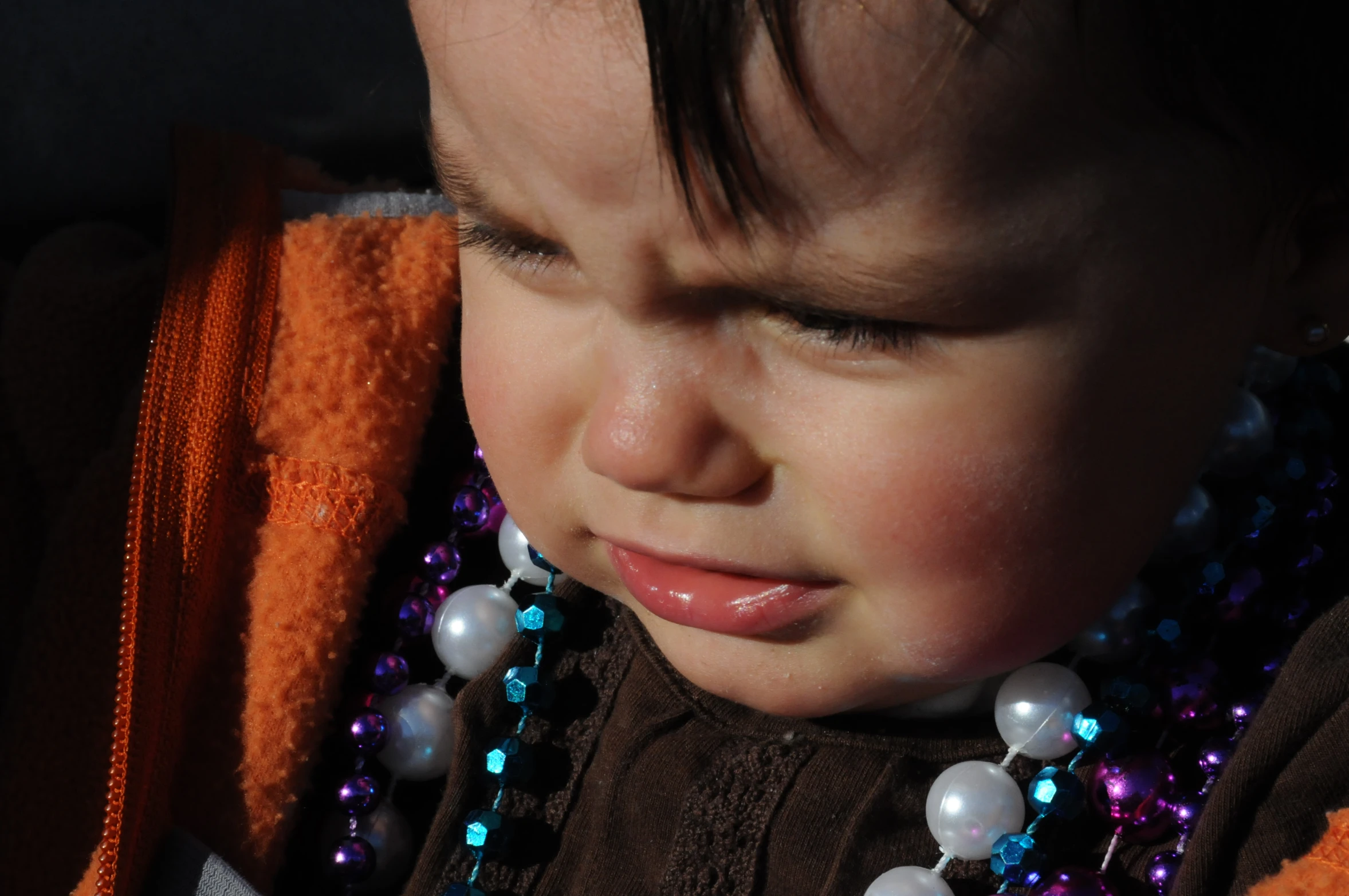 the young child is wearing beads and a sweater