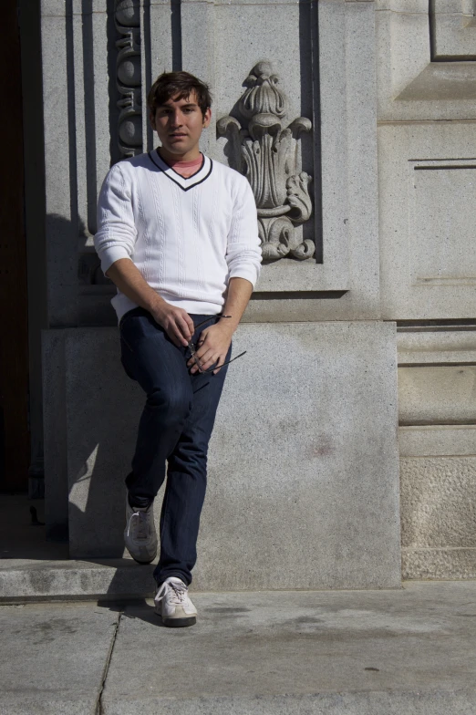 young man sitting on ledge near stone column