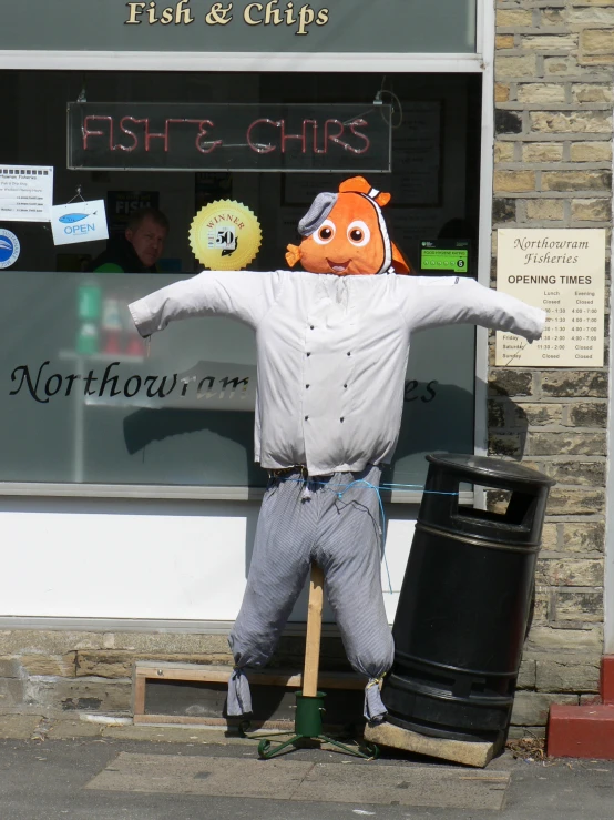 a man in an orange fish head is standing on a street