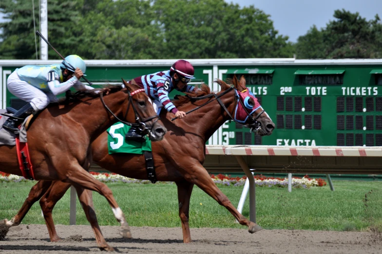 two jockeys are riding horses down the track