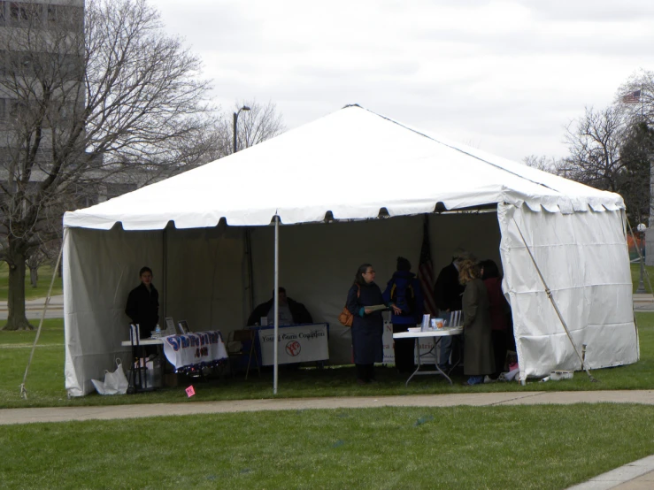 several people and their umbrellas outside in a tent