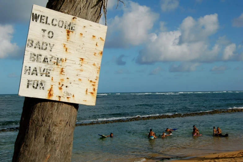 a sign saying welcome to any beach in the water