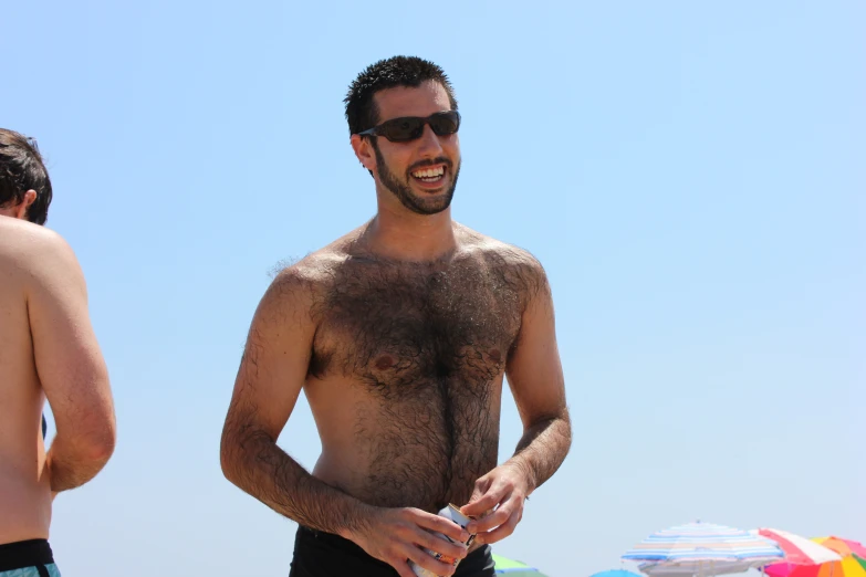 man without shirt on standing in front of a beach