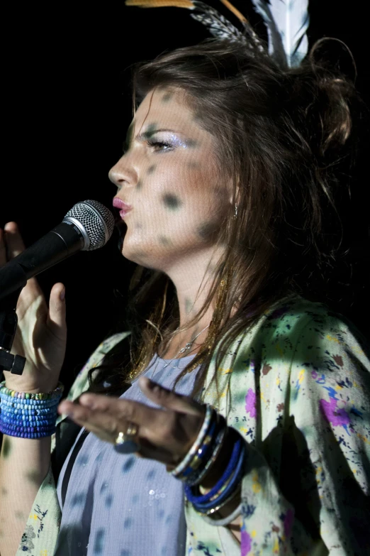 a woman singing into a microphone wearing feathers