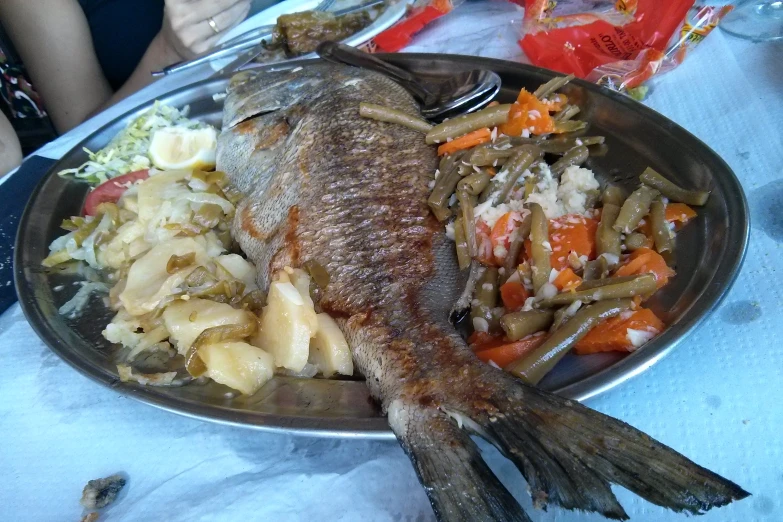 some fish is sitting on a pan full of food