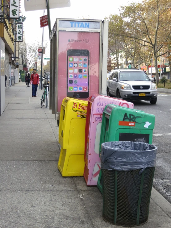 a row of vending machines line the sidewalk near a city street