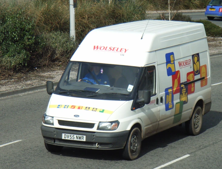 a white van on road near trees and bushes