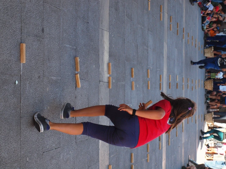 a woman in tights and a red shirt throwing some stick like material at someone