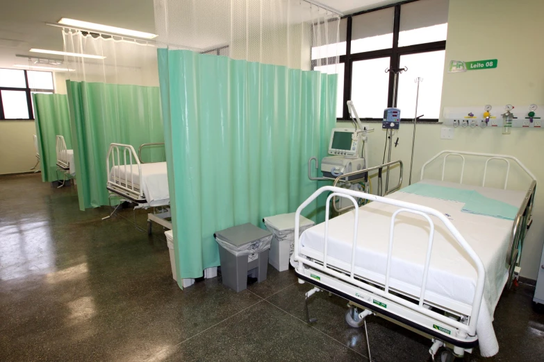 a hospital room with a medical bed and green privacy walls