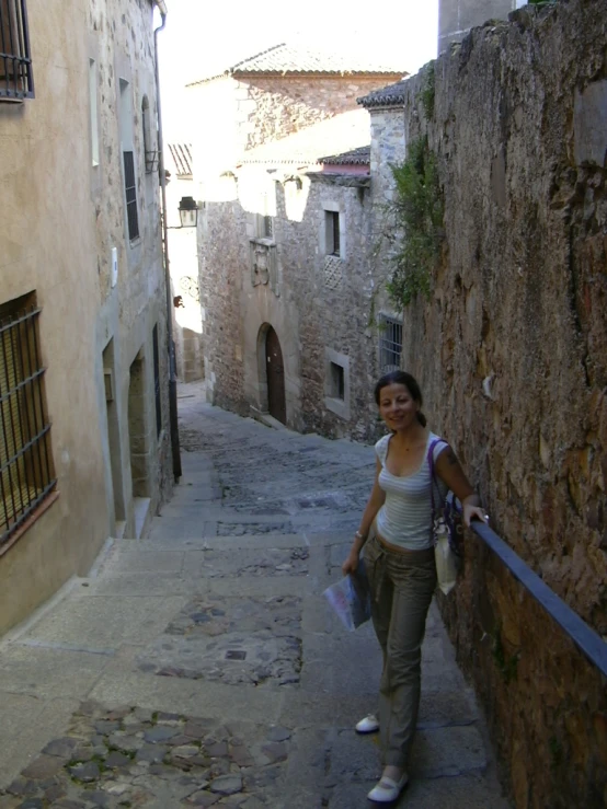 a woman is walking down a narrow alley way