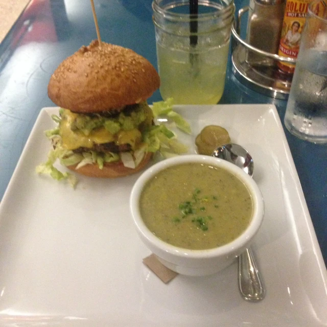 the sandwich is next to a bowl of soup on a tray